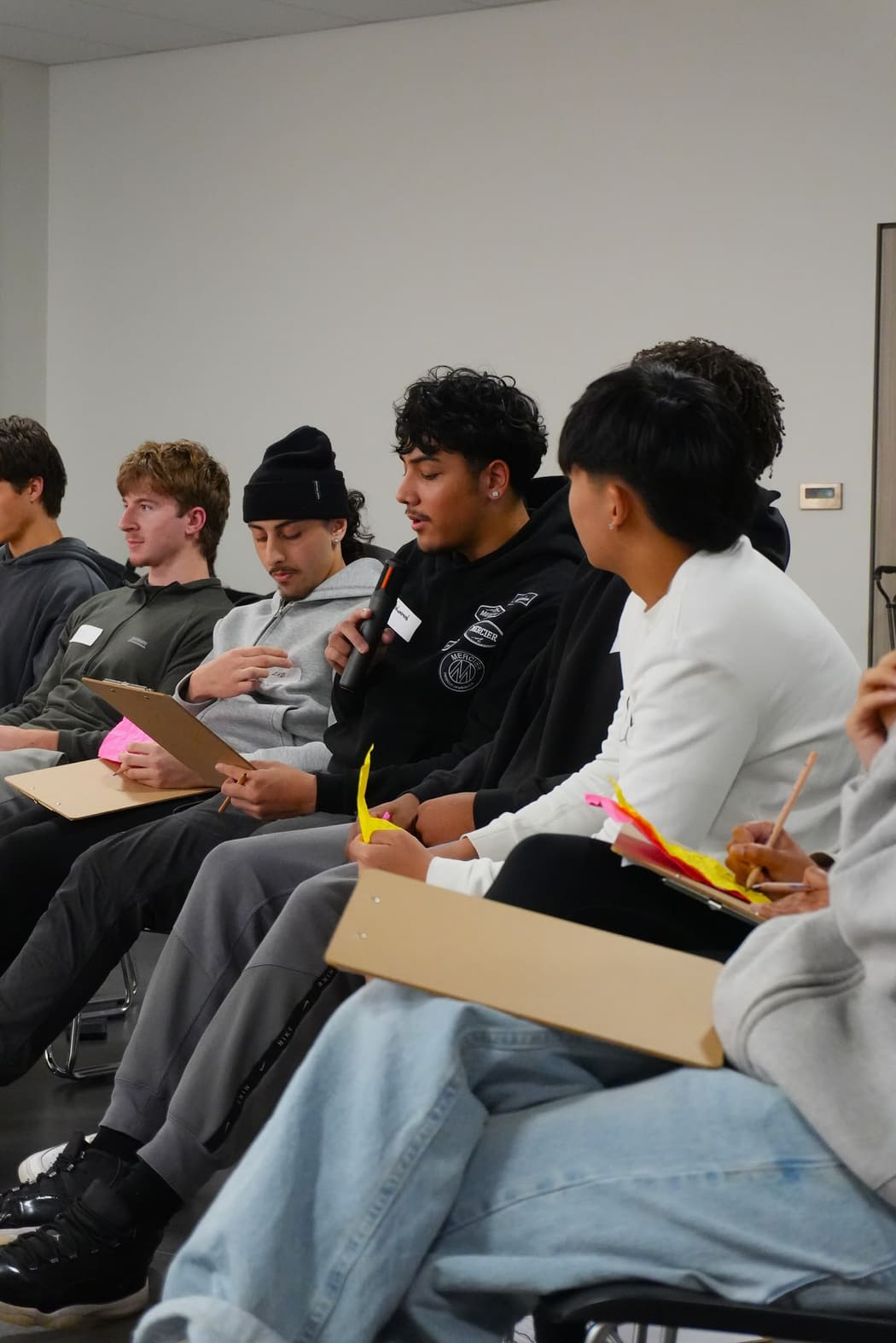 A young person speaking into a microphone while the group listens