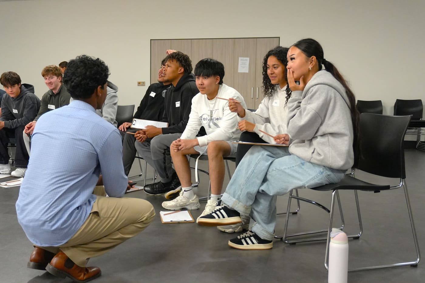A facilitator crouching to talk with a small group of seated participants