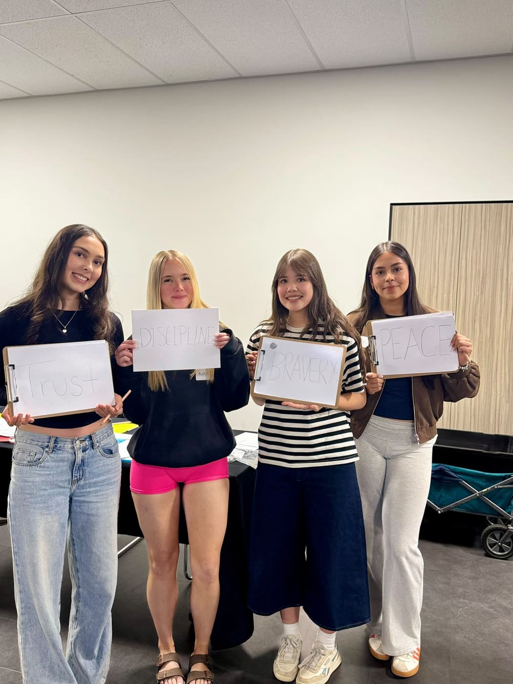 Four participants holding cards reading Trust, Discipline, Bravery and Peace