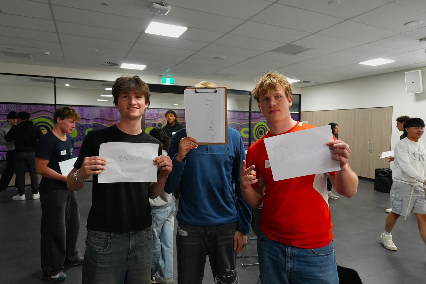 Three participants holding cards reading Discipline, Understanding and Generosity
